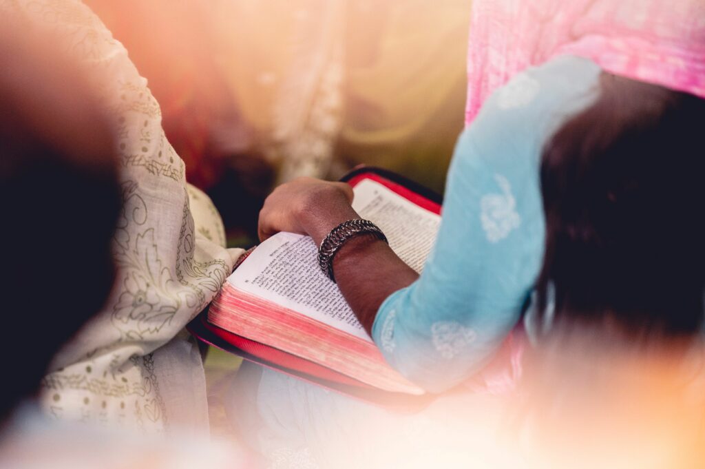Selective focus of a woman with a Holy Book and a headscarf worshiping in a church in India